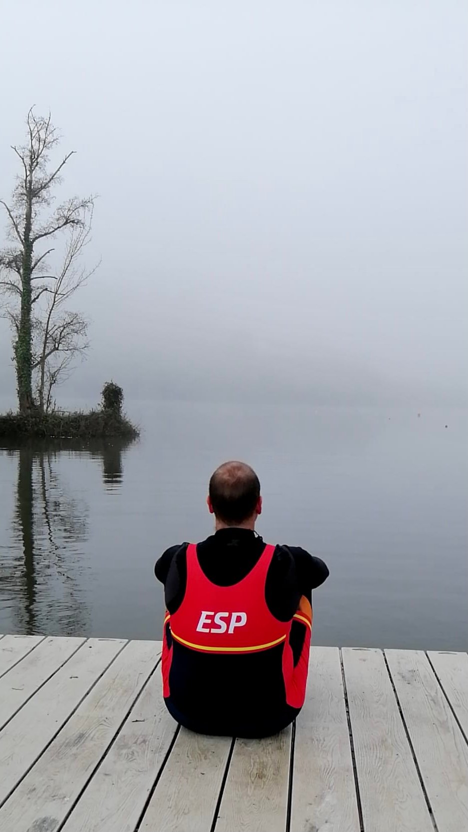 Sentado en el pantalán mirando al horizonte, con el mono de la selección española de remo