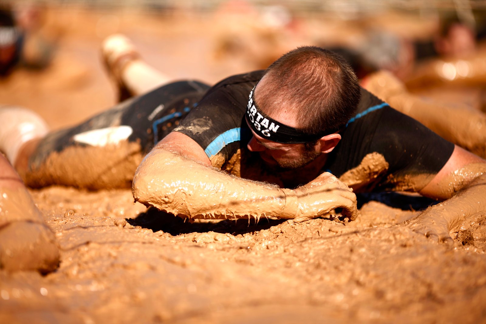 Foto reptando por el barro bajo los alambres superando la pista americana de la Spartan Race