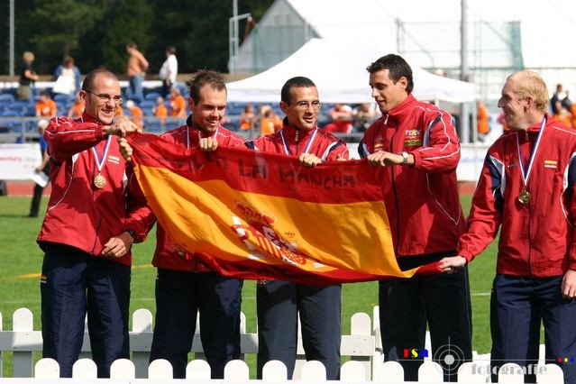 Foto en el podio con las medallas y agarrando entre todos una bandera de España