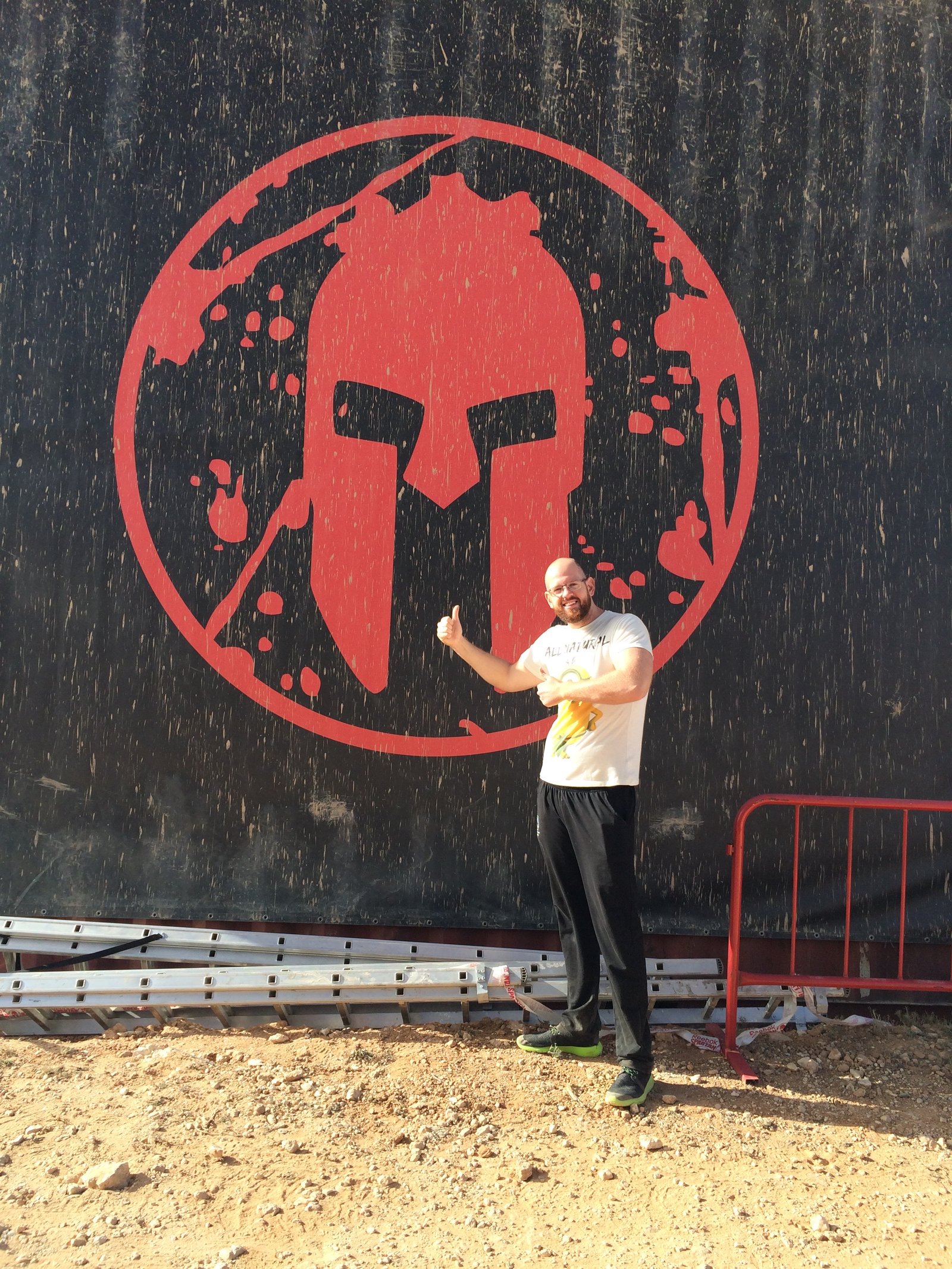 Foto de mi hermano David posando con el logo de la Spartan gigante en una pared