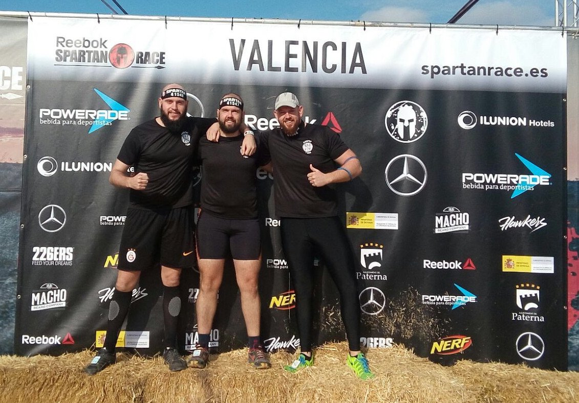 Foto de los 3 ya preparados posando delante de un cartel de la carrera en el circuito